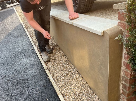 A worker applying a finishing coat to a garden wall.